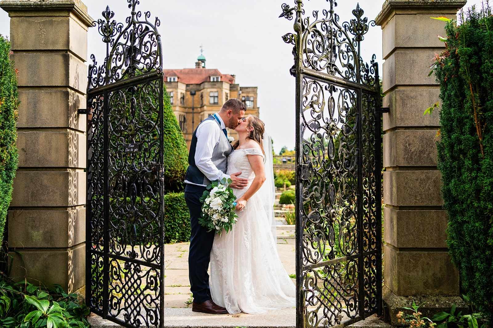 bride and groom have a kiss outside with iron gates either side ajar