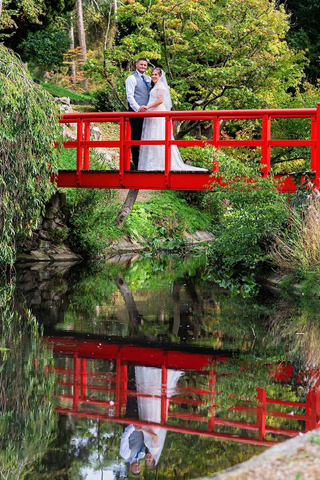 bride and groom stand on red bridge