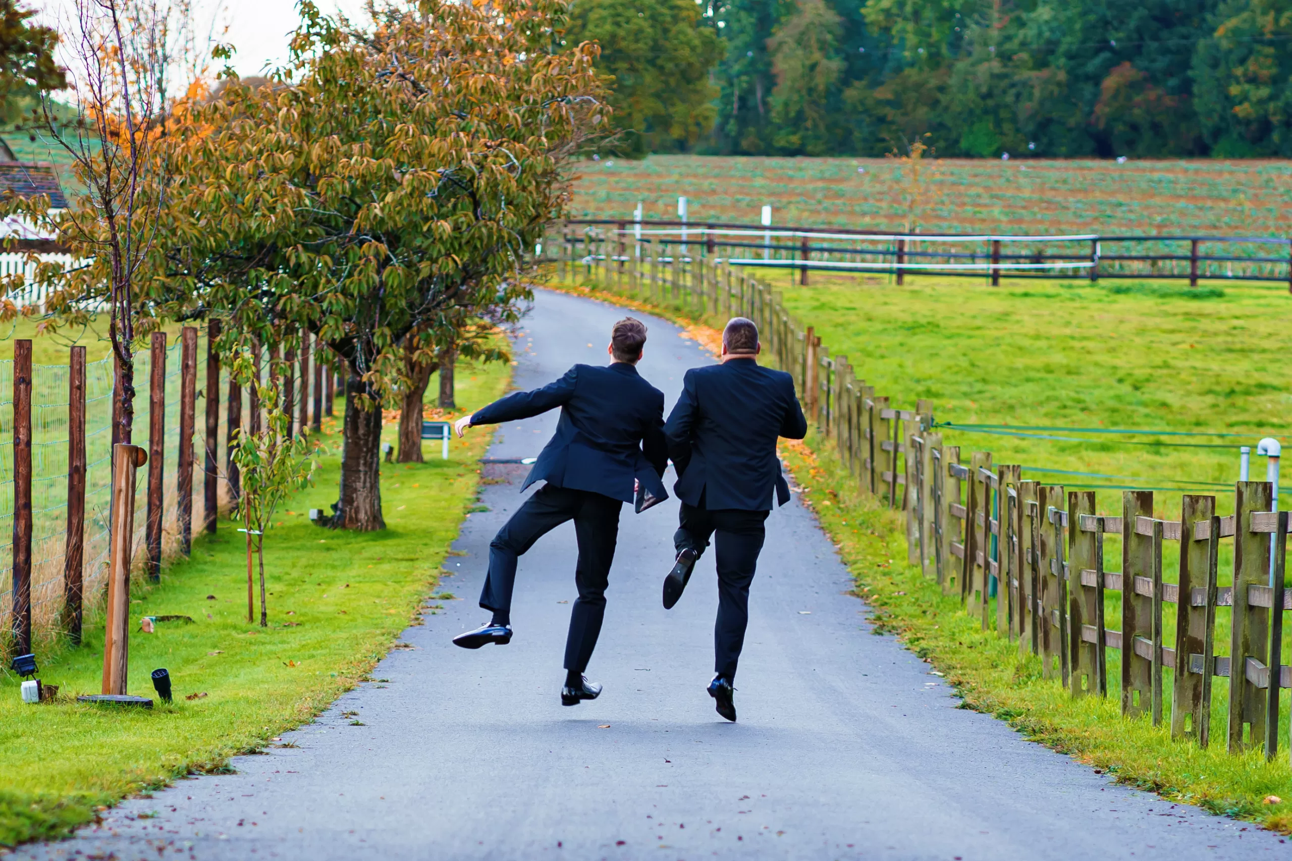 wedding supplier- give me sunshine. groom and his best man dancing down the road at quendon hall