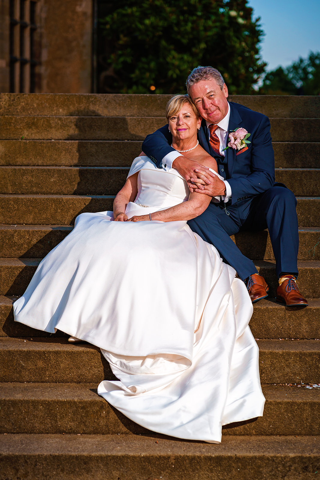 mature bride and groom sit on the steps to fanhams hall hertfordshire