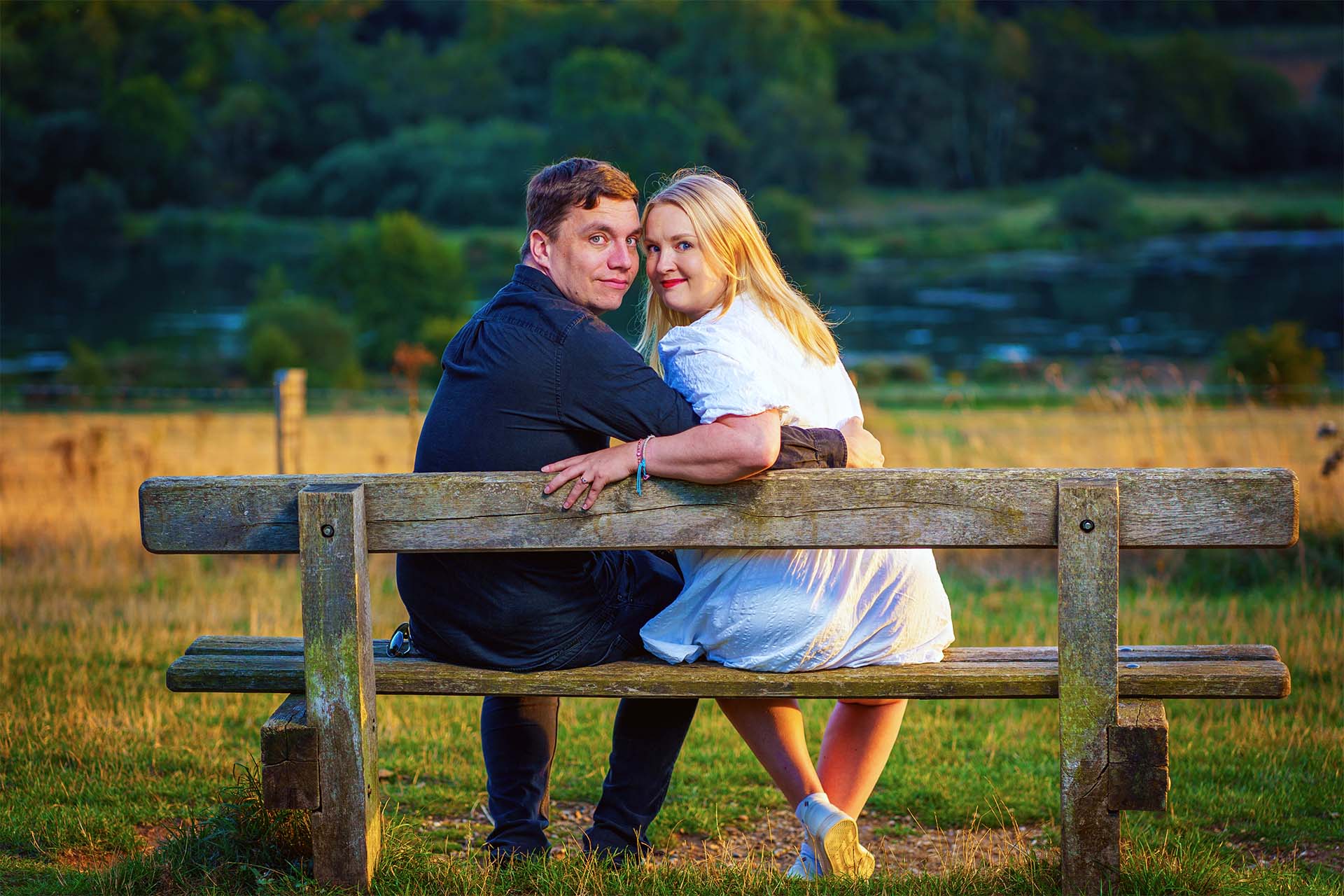 couple on a bench in the hertfordshire country side at their engagement shoot