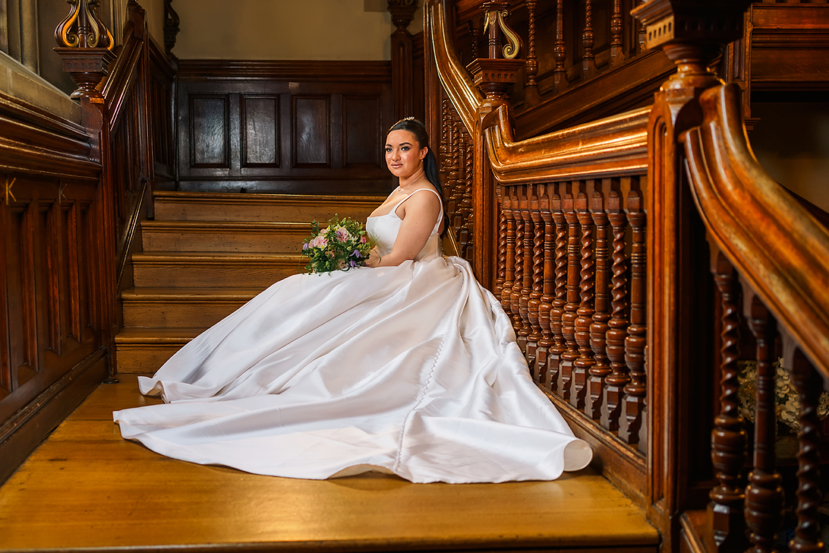 a bride sitting on the oak stairs at pendley manor hertfordshire.