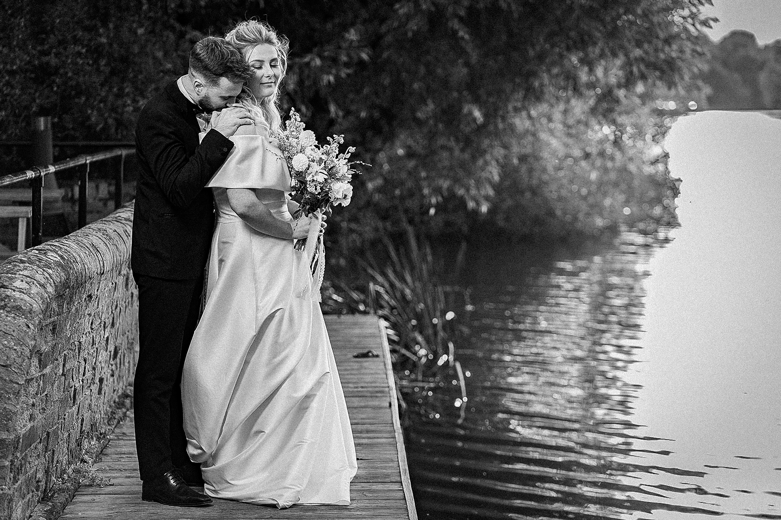 bride and groom embracing near waters edge