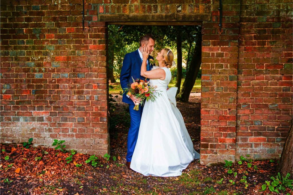 bride and groom standing outside in a brick gateway