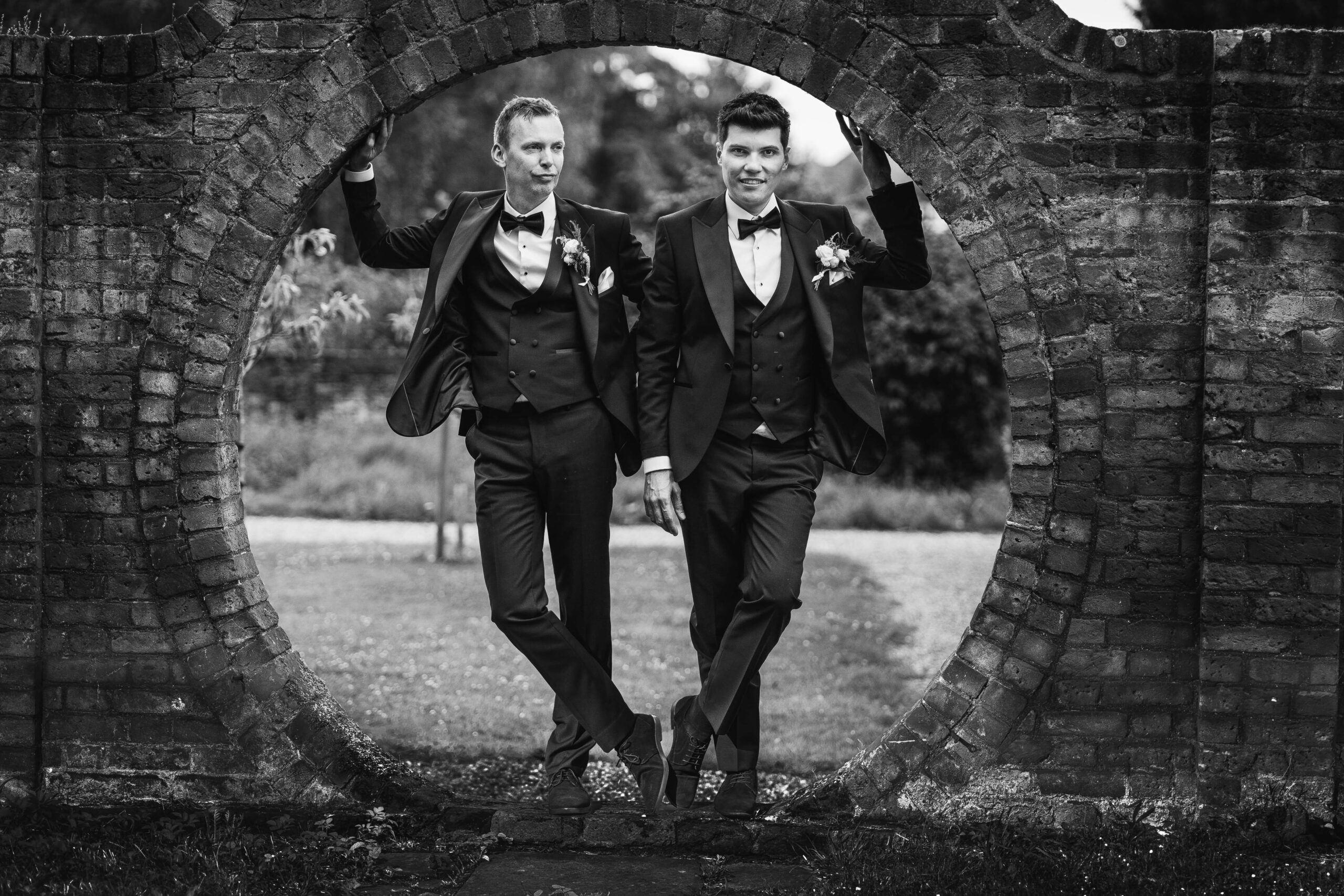 lgbtq+ - husband and husband in a brick circular archway.