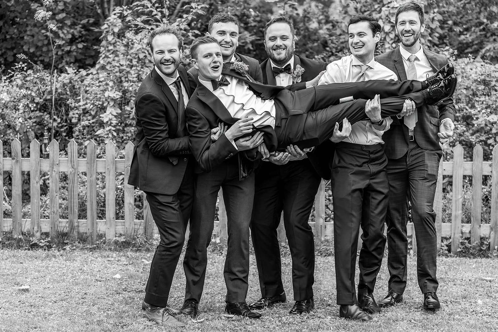 the waterside - all the groomsmen lifting the groom