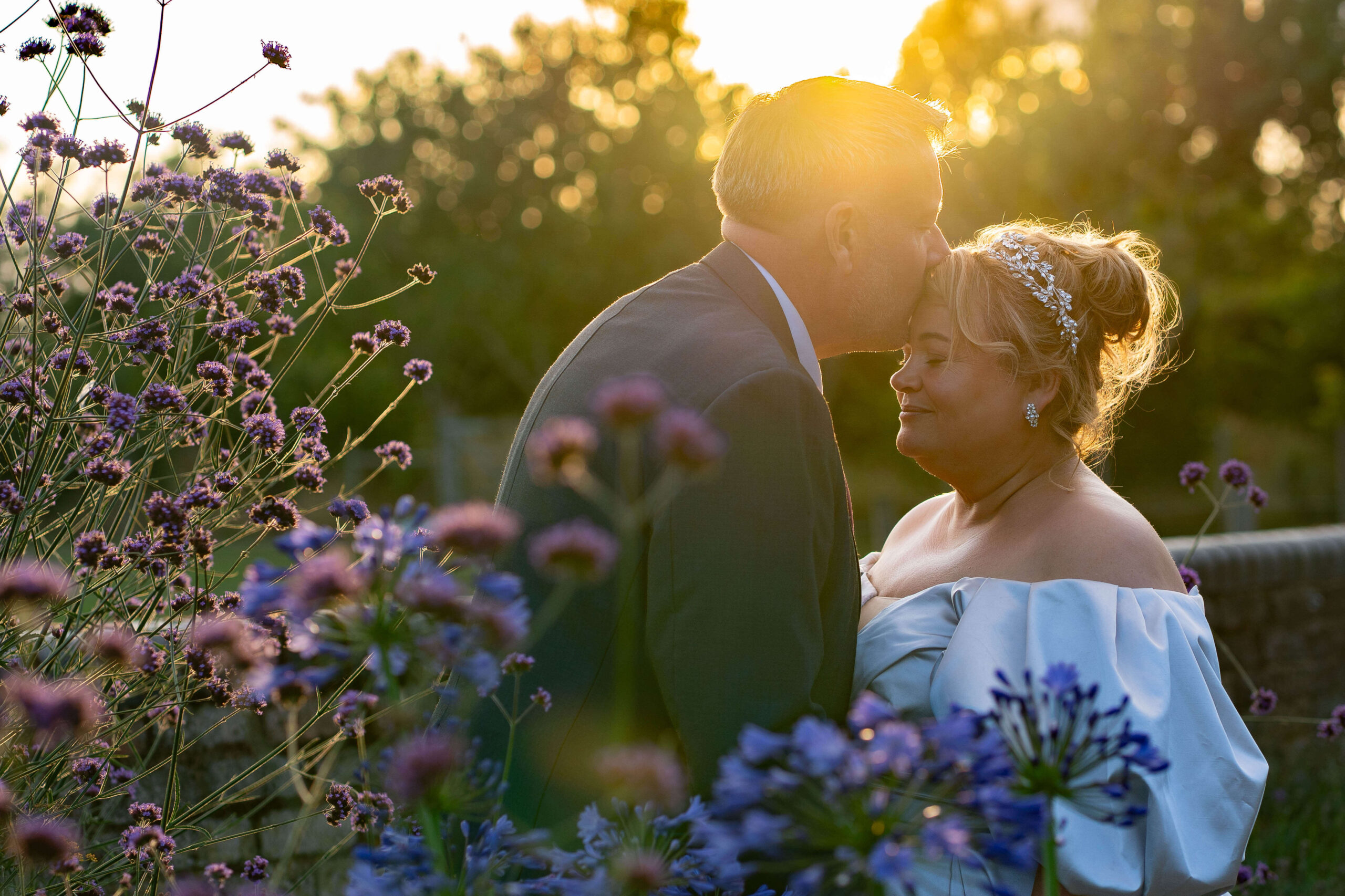 mature bride and groom at sunset. groom kissing bide on forehead